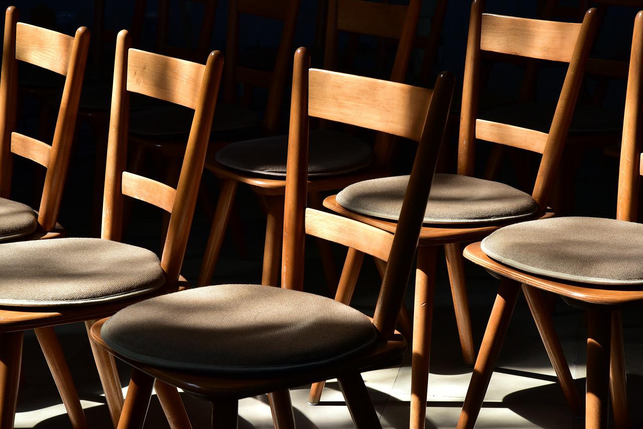 Sześć drewnianych tapicerowanych krzeseł w ciemnym pomieszczeniu